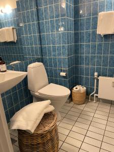 a blue tiled bathroom with a toilet and a sink at Holte lejlighed in Holte