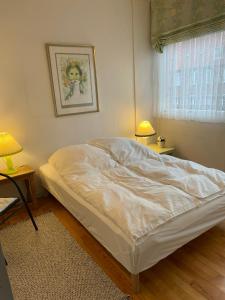 un letto bianco in una camera con due lampade di Holte lejlighed a Holte