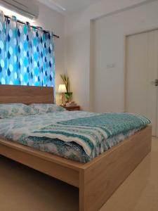 1 dormitorio con 1 cama grande y cortina azul en Sunshine 1BHK Penthouse @Virugambakkam, en Chennai