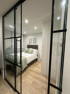 - une chambre avec un lit et un mur en verre dans l'établissement Luxury Capella Court, à Londres