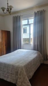 a bedroom with a large bed and a window at Apartamento no Centro Parq Halfeld Juiz fora in Juiz de Fora
