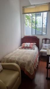 a bedroom with a bed and a window and a couch at Apartamento no Centro Parq Halfeld Juiz fora in Juiz de Fora