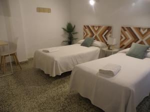 Habitación con 2 camas, sábanas blancas y almohadas verdes. en Hostal Paco Marbella, en Marbella