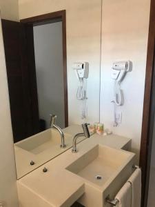 een badkamer met een wastafel en een spiegel bij GIRASSÓIS - Suítes in Pipa