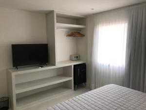 1 dormitorio con TV, 1 cama y ventana en GIRASSÓIS - Suítes, en Pipa