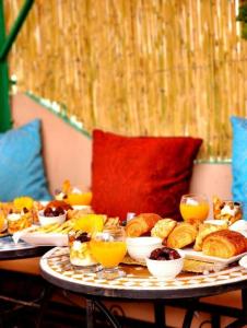 uma mesa com diferentes tipos de pão e sumo de laranja em Riad Dar Barae em Fès al Bali
