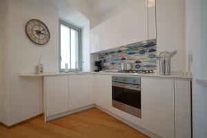 eine Küche mit weißen Schränken und einer Uhr an der Wand in der Unterkunft The charming house in Taormina