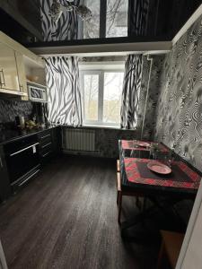 una pequeña cocina con mesa y ventana en Квартира по Республике 16/2, en Karagandá