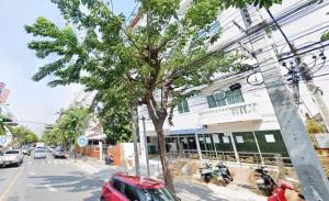 un albero sul lato di una strada accanto a un edificio di Wellness Mansion Hotel a Dusit