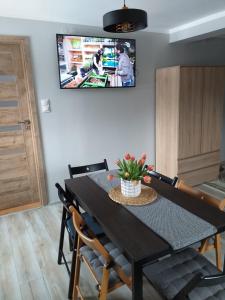 a dining room table with chairs and a tv on the wall at Kulibaba in Bystrzyca Kłodzka