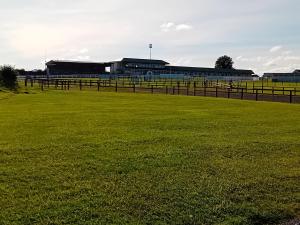 a field of green grass with buildings in the background at Cuan na bPiobairí in Mullingar