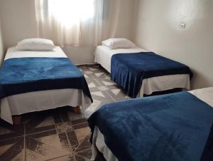 イタペバにあるPousada Li Artの青いカバーのベッド2台が備わる客室です。