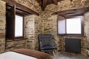 een slaapkamer met een stoel en een bakstenen muur bij Casa Rural Lar de Sanxes in Lugo