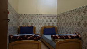 a bedroom with two beds with blue sheets and wallpaper at Auberges Des Jeunes Casablanca in Casablanca