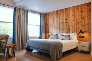 Un dormitorio con una cama con paredes de madera y una ventana en The Brownswood en Londres