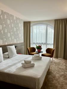 a bedroom with a large bed with two towels on it at Dali Hôtel Montauban in Montauban