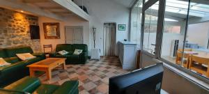 a living room with green furniture and a tv at La Jubilotte in Beaumes-de-Venise