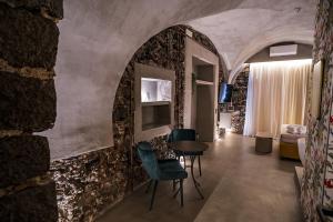 Habitación con pared de piedra, mesa y sillas. en CHARME Catania Central Suites en Catania