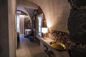CHARME Catania Central Suites في كاتانيا: حمام مع حوض على جدار حجري