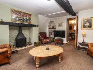 a living room with a table and a fireplace at Mouse Hole Cottage in Cheltenham