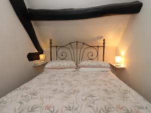 1 cama en un dormitorio con 2 lámparas en 2 mesas en Mouse Hole Cottage en Cheltenham