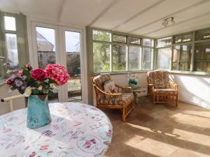 una habitación con una mesa con un jarrón de flores en Mouse Hole Cottage en Cheltenham