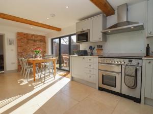 a kitchen with white appliances and a table with chairs at Blossom Cottage in Chipping Campden