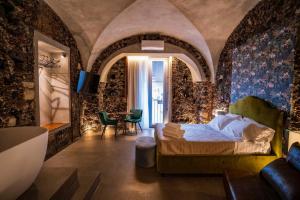 una camera con un letto in una stanza con pareti in pietra di CHARME Catania Central Suites a Catania