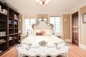 a bedroom with a white bed with a large headboard at Stone Chalet Bed & Breakfast Inn in Ann Arbor