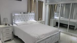 ein weißes Schlafzimmer mit einem Bett und einem Spiegel in der Unterkunft Rijos tower 3 in Santo Domingo