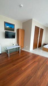 uma sala de estar com pisos em madeira e uma televisão na parede em Pokoje na Cyplu em Mrągowo