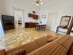 ein Wohnzimmer mit einem Sofa, einem TV und einem Tisch in der Unterkunft Piazzetta San Giovanni B&B in Specchia