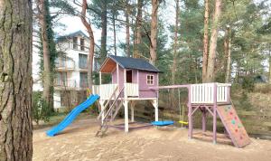 a playground with a house and a slide at BURSZTYNOWO Domy z saunami i jakuzzi in Ostrowo