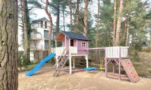 a playground with a house and a slide at BURSZTYNOWO Domy apartamentowe in Ostrowo