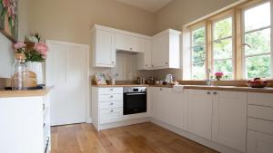a kitchen with white cabinets and a black oven at The Cotswold Hideaway - Boutique Cottage in Long Compton