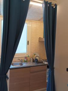 ナポリにあるB&B Maryflowerのキッチン(シンク付)、青いカーテン付きの窓