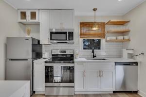 una cocina blanca con armarios y electrodomésticos blancos en Beachy 3BD Bungalow One Block from Scenic Walkway, en Oak Island
