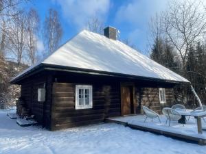 a cabin with a snow covered roof in the snow at A to Cichata - Agroturystyka in Odrzykoń