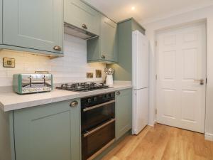 a kitchen with green cabinets and a stove at Fistral Bay Cottage in Newquay