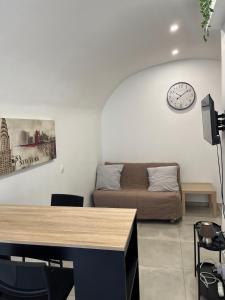 uma sala de estar com um sofá e um relógio na parede em Agréable studio en plein coeur de ville em Saint-Jean-de-Védas