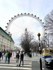 a large ferris wheel in a city with people crossing a street at Waterloo Central London in London