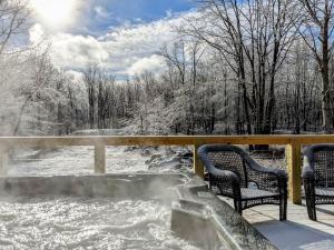 a snow covered deck with two chairs and a hot tub at Skypine Lodge - Log Lodge Atop the World in Jim Thorpe