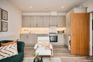 a living room with a green couch and a kitchen at The Harlesden Hideout - Charming 2BDR Flat in London