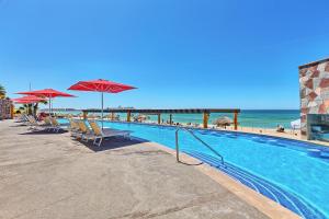 - une piscine avec des chaises longues et des parasols à côté de la plage dans l'établissement Sonoran SKY #910, à Puerto Peñasco