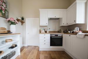 a kitchen with white cabinets and a black oven at The Cotswold Hideaway - Boutique Cottage in Long Compton