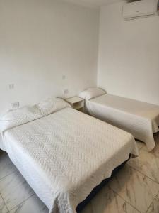 2 camas en una habitación con paredes blancas en SONSOLES HOTEL en Paso de la Patria