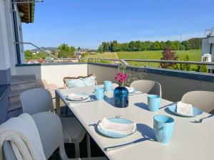a table and chairs on a balcony with a view at GLÜCKSMOMENT - beeindruckende Ferienwohnung mit Pool in Seekirchen am Wallersee