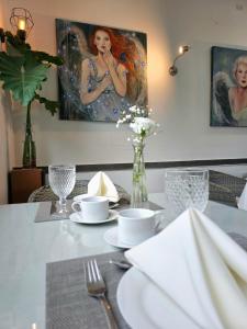 a dining room table with a white table cloth and a painting at Hotel Oasis-Dream Holidays - La Petite France in San Bernardino