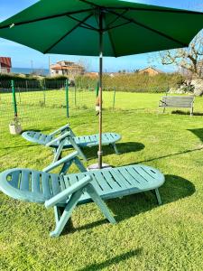 two picnic tables and an umbrella with two chairs at Alojamientos Robustiana in Santander