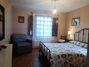 a bedroom with a bed and a chair and a window at La Xana Ribadesella in Ribadesella